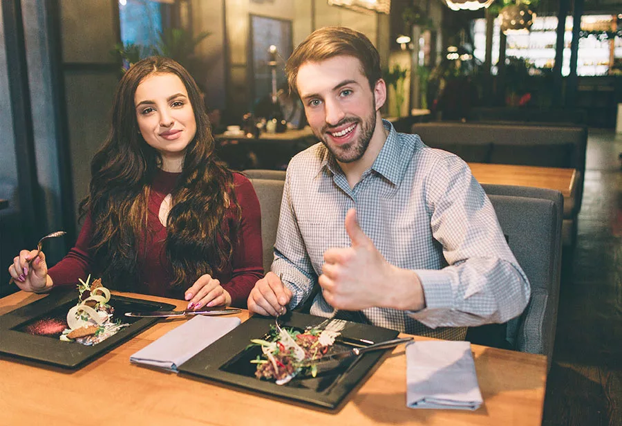 Man giving thumbs up in restaurant booth.